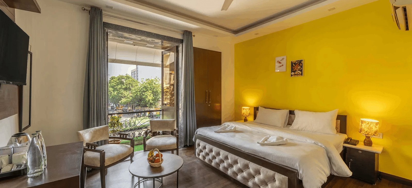 A hotel room with twin beds, yellow accents, and a view of greenery through the window - Lime Boutique Bed & Breakfast | Nehru Place Metro